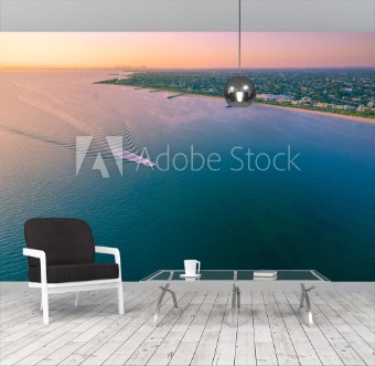 Picture of Aerial view of boat sailing across Port Phillip bay with Melbourne coastline and suburban areas in the background at beautiful sunset